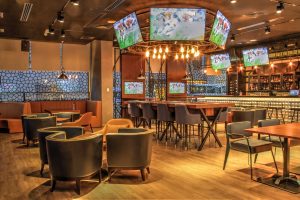 A contemporary sports bar featuring multiple screens, stylish furniture, and ambient lighting for a perfect entertainment experience.