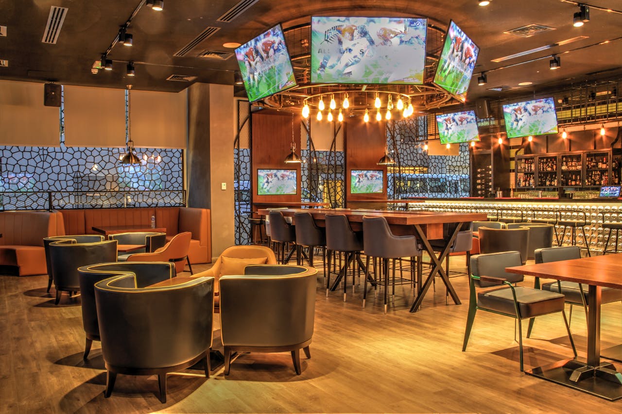 A contemporary sports bar featuring multiple screens, stylish furniture, and ambient lighting for a perfect entertainment experience.