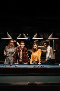 Young adults playing billiards, enjoying leisure time and friendship indoors.